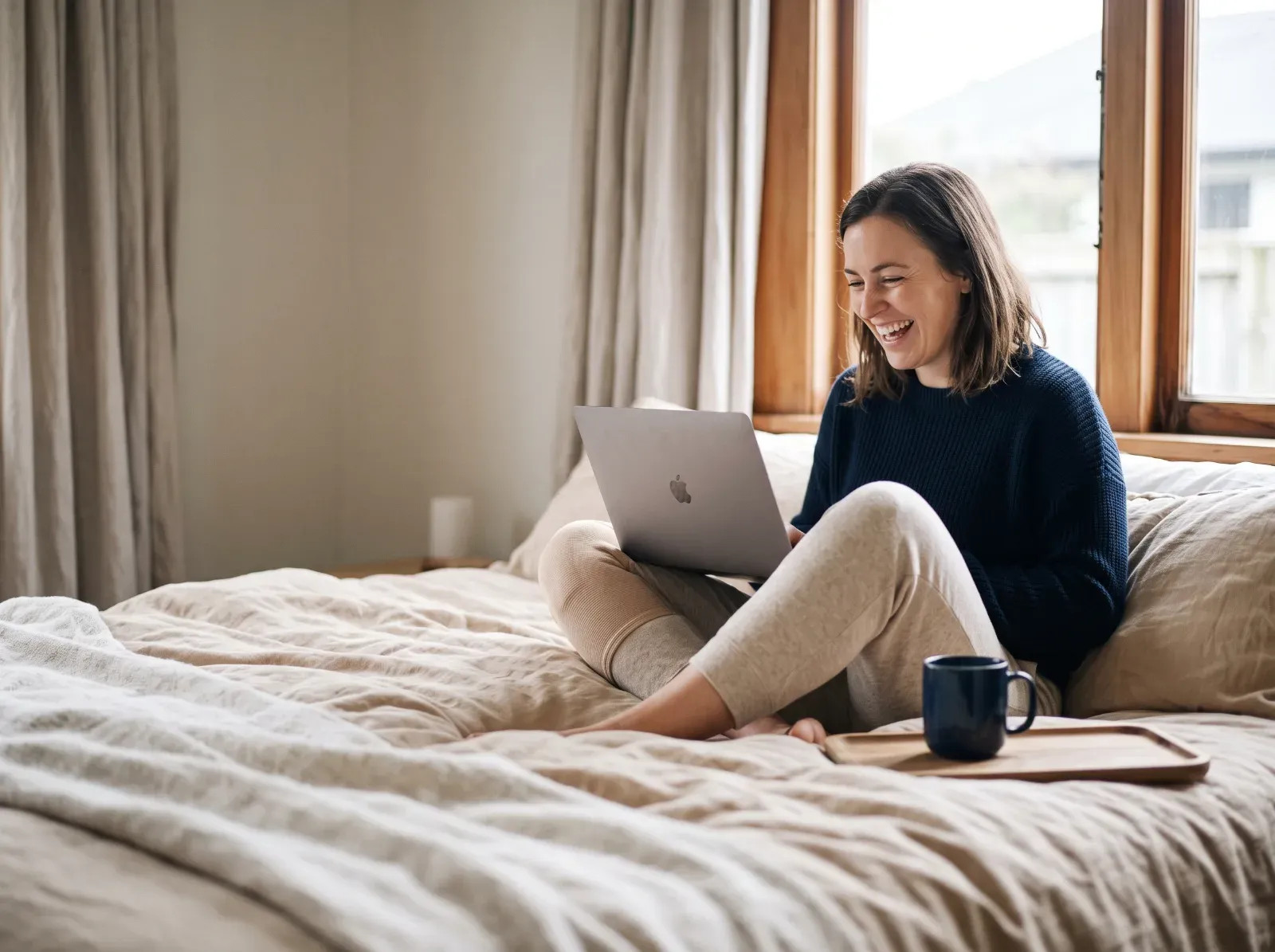 A woman sitting up in bed with a laptop