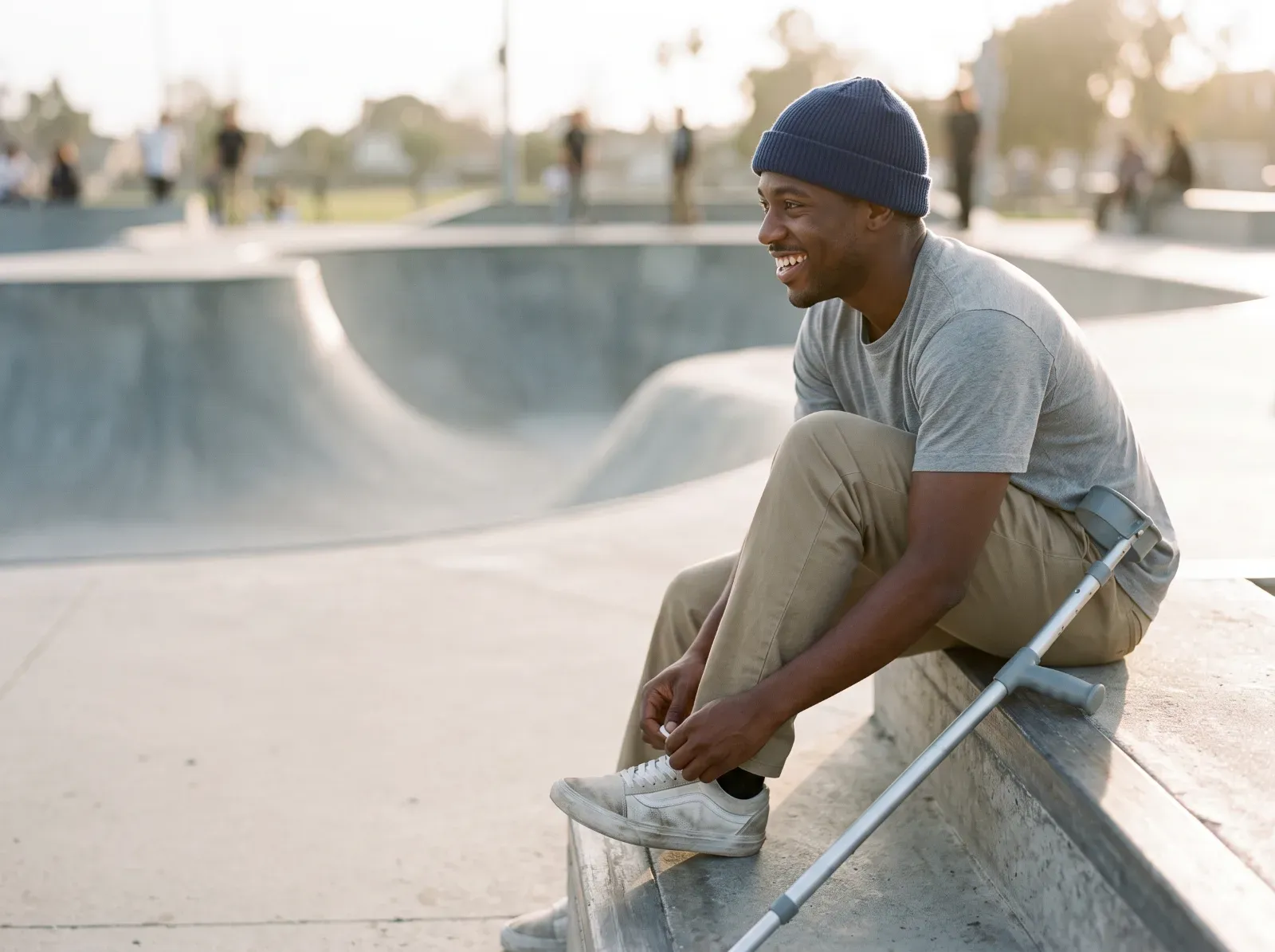 A man with a crutch tying his shoe at a skatepark